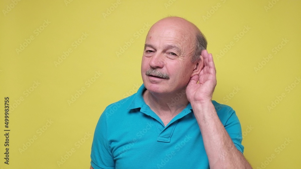Senior man trying to listen to the latest news holding hand near ear